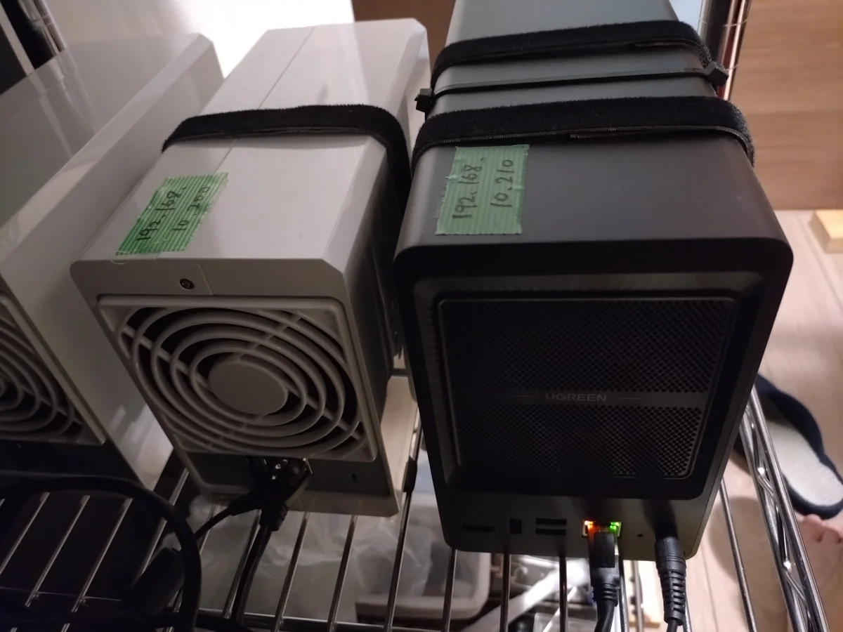 運営者が24時間稼働させている無印UGREEN NASync DXP2800(右・黒)の背面。2.5GbEのLANポートが1つだけ搭載され、LAN緑LEDが点灯している