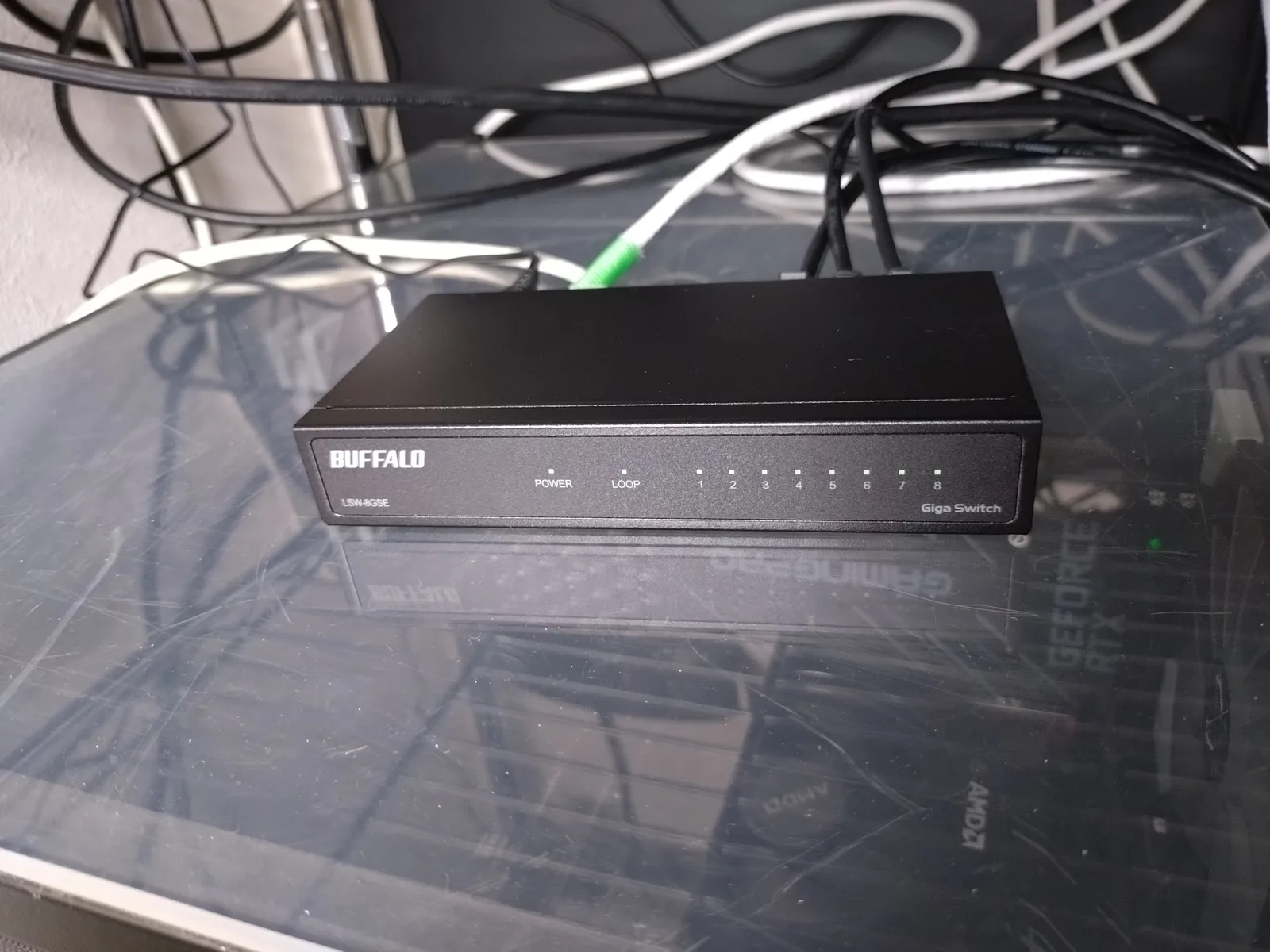 BUFFALO LSW-8GSEを斜め上から見た写真。金属筐体の本体奥側にLANケーブルが複数本挿さっており、前面のPOWER・LOOP・1〜8のランプ表記が見える