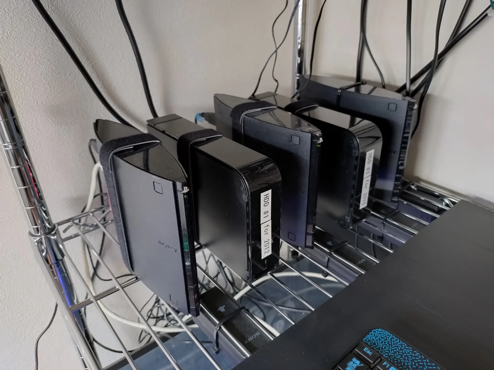 メタルラックに縦置きで並んだSIE製nasneと外付けHDD。HDDには手書きのラベルが貼られている